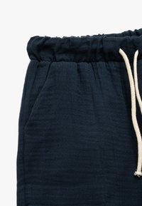 Navy blue drawstring shorts, valmistettu tekstuurisesta kankaasta; sisältää elastisen vyötärön ja sivutaskut käytännöllisyyden vuoksi.