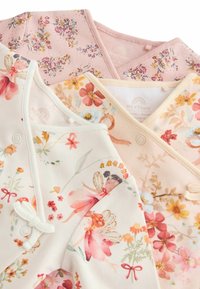 Tre indumenti per bambini in tessuto morbido: uno rosa con motivi floreali, uno crema con illustrazioni di fate e uno pesca con fiori colorati.