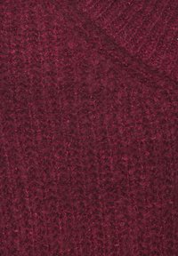 Dunkelroter gestrickter Wollstoff mit einem strukturierten Muster und einer weichen, flauschigen Oberfläche.