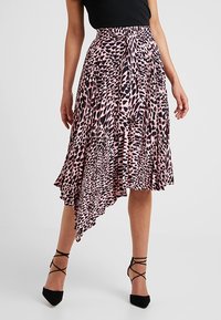 Asymetrická růžová sukně s černým leopardím vzorem, plisovaný design, lehká tkanina, hotový lem, nošena s černými sandály na podpatku.
