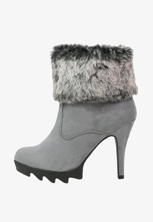Stivaletto grigio in suede con tacco alto, suola nera scolpita e polsino in pelliccia sintetica grigia pieghevole.