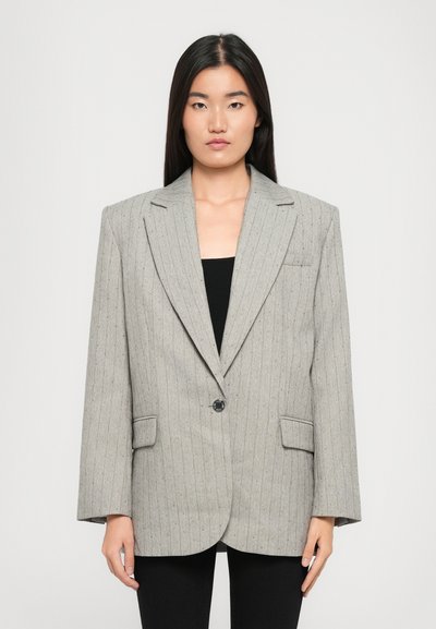 Hellgrauer Blazer aus strukturiertem Stoff mit vertikalen Nadelstreifen, Ein-Knopf-Verschluss und zwei frontalen Taschen. Quadratische Schultern.