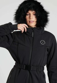 Schwarze isolierte Jacke mit Kunstfellkapuze, tailliertem Gürtel, hohem Kragen und mit Reißverschlüssen versehenen Taschen. Mit Logodetail auf der oberen linken Brust.