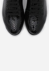 Černé tenisky s lesklým, hadím vzorem, rovnoměrným povrchem, kulatou špičkou a šesti plochými tkaničkami. Elegantní design.