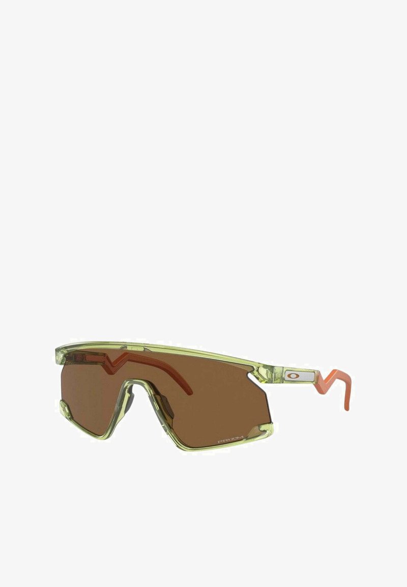 Lunettes de soleil avec une monture translucide vert lime, des verres marron et des accents orange ; design angulaire avec un look sportif et des branches épaisses.