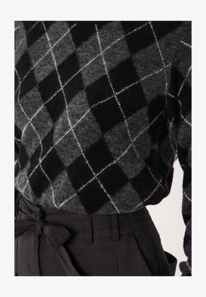 Grijs en zwart argyle-patroon trui van zachte stof, gecombineerd met zwart high-waisted broek met een gestrikte ceintuurdetail.