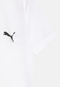 Camiseta blanca de manga corta hecha de tela suave, con un contorno del logo de Puma en negro en la parte izquierda del pecho.