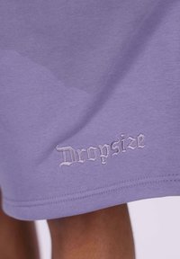 Lila Baumwollshorts mit strukturiertem Finish und gesticktem "Dropsize"-Logo in Weiß am Saum.