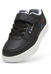 Zapatilla negra de cuero con suela blanca, caja de dedos perforada, cordones negros y logo de Puma. Presenta acentos de BMW Motorsport en azul y rojo.