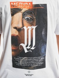 Hvid bomulds t-shirt med et grafisk print af et ansigt og svulme mønstre, overlejret med rødt tekst, der læser "МЕДУЗА" og yderligere tryk nedenfor.