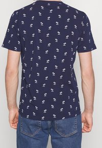 T-shirt a maniche corte blu navy con motivo di palme bianche, scollatura a girocollo, realizzato in tessuto di cotone, caratterizzato da un fit rilassato.