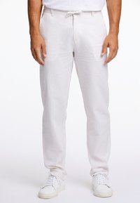 Lightweight, white linen pants with a relaxed fit, featuring a drawstring waistband and subtle texture. Paired with white sneakers.