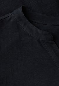 Chemise à manches courtes bleu marine avec un col rond et une texture subtile, présentant des coutures visibles et une finition en tissu lisse.