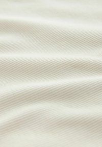 Tissu crème doux avec une fine texture diagonale en relief et de légers plis.