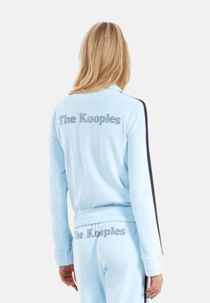 Giacca da track in velour azzurro chiaro con "The Kooples" in strass, strisce laterali nere e polsini e orlo a costine.
