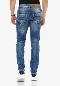 Slim-fit blauwe denim jeans met een vervaagde afwerking. Bevat twee achterzakken, een leren label met de merknaam en contrasterende stikdetails.