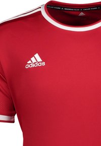 Rood sportshirt van gladde stof. Heeft een witte bies op de kraag en mouwen, met een wit Adidas-logo op de linkerborst.