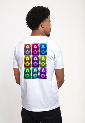 Hvid kortærmet t-shirt med et gitter af farverige grafiske tryk på bagsiden, der viser et stiliseret ansigt med et 'A' motiv.