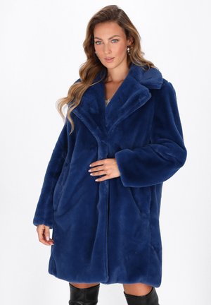 Cappotto di pelliccia sintetica blu navy con un ampio colletto, maniche lunghe e profonde tasche laterali; texture morbida e vestibilità comoda.