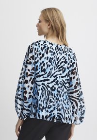 Blusa in chiffon leggero con stampa animale blu e nera, caratterizzata da maniche lunghe e design posteriore plissettato.