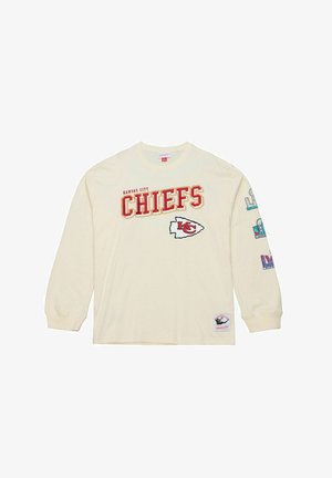Maglietta a manica lunga color crema con la scritta "Kansas City Chiefs" in lettere rosse e gialle, con un logo bianco e grafiche colorate sulle maniche.