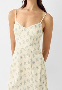 Šaty s květinovým vzorem v světle žluté barvě, vyrobené z lehké látky. Mají tenká ramínka a krajkový lem u výstřihu. Střih do áčka.