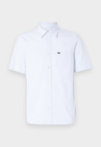 Lyhythihainen, vaaleansininen nappipaita, jossa valkoiset pystysuorat raidat. Vasemmassa rintataskussa vihreä logo. Puuvillasekoitetekstuuri.