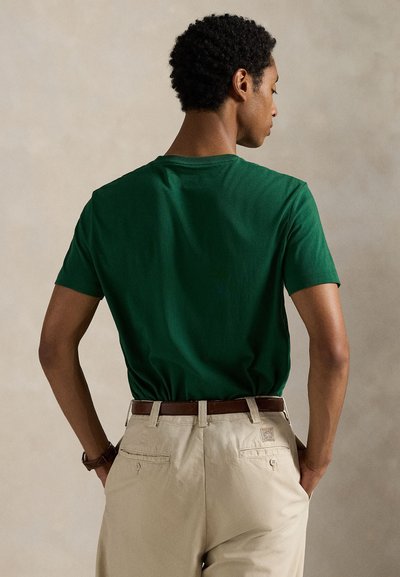 Πράσινο βαμβακερό μπλουζάκι με κοντά μανίκια και στρογγυλή λαιμόκοψη, σε συνδυασμό με χακί παντελόνι και καφέ ζώνη. Η πίσω όψη αναδεικνύει την απλότητα στο σχέδιο.