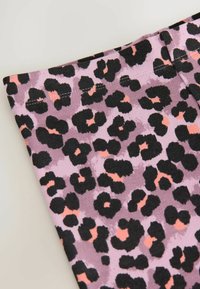 Stretchy tygbyxor med en lila bas och svart samt korallfärgad leopardmönster. Mjuk textur med fina stygn längs midjebandet.