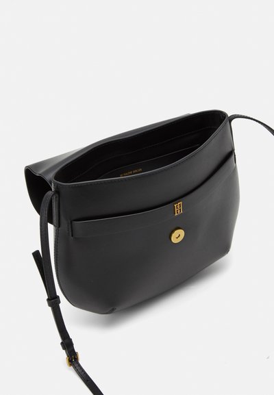 Sac en cuir noir porté travers avec un design structuré, doté d'une fermeture à bouton doré et d'une sangle ajustable. Texture lisse et style minimaliste.