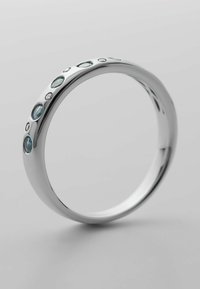 Silberring mit einer glatten, polierten Oberfläche, der entlang einer Seite mit verschiedenen runden Aquamarin- und klaren Edelsteinen besetzt ist.