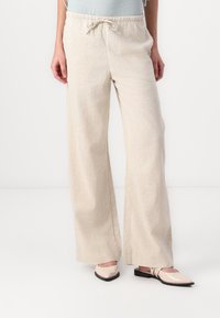 Beige Leinen Culotte-Hosen mit elastischem Bund und Kordelzug. Glatte, leichte Textur; kombiniert mit spitzen Ballerinas.