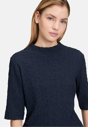 Navyblaue Bluse aus strukturiertem, knitterigem Stoff, mit hohem Ausschnitt und kurzen Ärmeln. Schlichtes, einfarbiges Design ohne Muster oder Verzierungen.