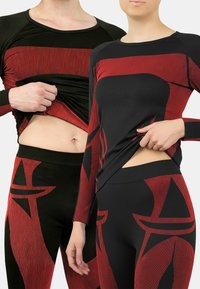 Black and red activewear featuring a striped design. The long-sleeve top has raglan sleeves, while the leggings have an abstract pattern.