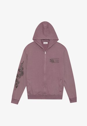 Mikina s kapucňou a zipsom v prachu ružovej farbe, s rebrovanými manžetami, bočnými vreckami a grafickou potlačou na ľavom rukáve. Mäkká textúra látky.
