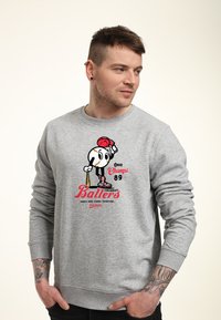 Grå sweatshirt med en tecknad basebollfigur, röd keps, texten "Ohio Champs 89" och "Cincinnati Ballers" i fet röd stil.