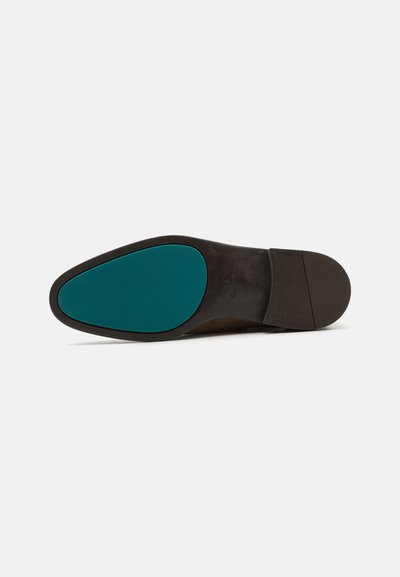 Semelle de chaussure avec une base en caoutchouc noir et un accent turquoise. La forme est effilée avec une texture lisse et un design de bout arrondi.