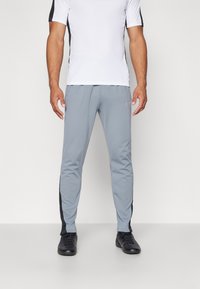 Grijze sportbroek met zwarte accenten aan de zijkanten, gemaakt van lichtgewicht materiaal. Heeft een tapering fit en een elastische tailleband voor comfort.