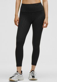 Melna ar rakstu leggings ar augstu jostas vietu. Materiāls ir elastīgs un pieguļošs. Saskaņots ar baltām un melnām sporta apaviem.