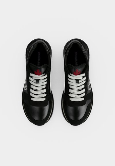 Paire de baskets en cuir noir avec lacets blancs et détail de feuille d'érable rouge sur la languette, vue de dessus sur fond blanc.
