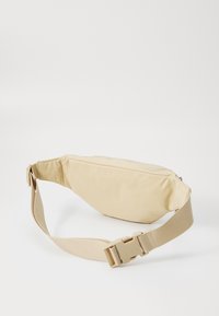 Borsa in nylon beige a vita con chiusura a zip, design piatto e tracolla regolabile con fibbia in plastica. Texture liscia, senza motivi visibili.