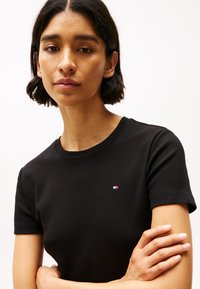 Zwarte korte mouwen t-shirt van katoen, met een klein merklogo op de linkerkant van de borst en een ronde halslijn.
