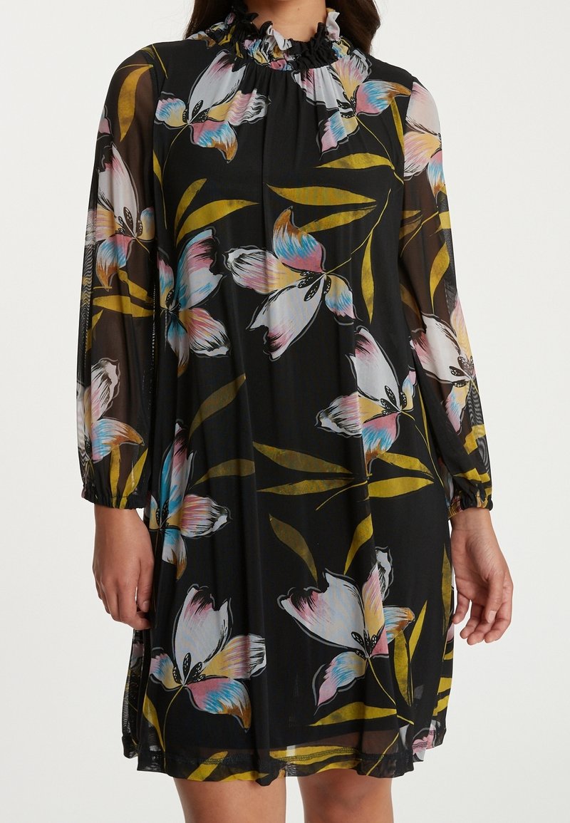 Vestido negro con mangas largas y transparentes, patrón floral en rosa y azul, escote fruncido y corte holgado, con acentos de hojas verdes.