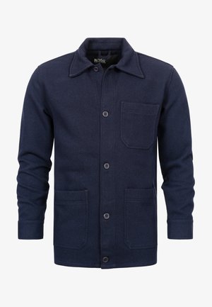 Marinblauwe herringbone jas van gestructureerde stof, met een puntige kraag, voorknopsluiting en twee grote voorzakken.