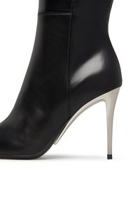 Stivale alto in pelle nera con un design elegante, tacco a stiletto argento metallico e texture liscia. Presenta una punta appuntita e una caviglia aderente.