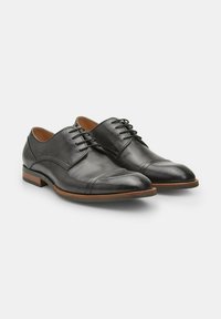 Chaussures habillées en cuir noir avec une finition lisse, bout rond et un laçage. Présentent une semelle intermédiaire marron et un talon bas empilé.
