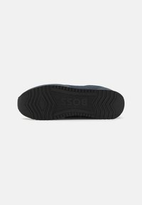 Sole nera di sneaker con un motivo testurizzato per la presa. Presenta il logo "BOSS" stampato nella gomma vicino al tallone e un design a profilo basso.