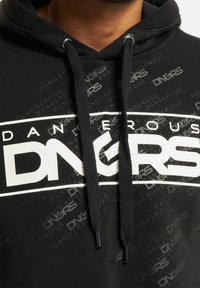Sudadera negra con tejido texturizado, que presenta un logotipo gráfico en blanco "DANGEROUS" y letras de acento. Incluye cordones negros y terminales de metal.