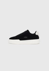Adidași negri cu talpă albă și tab cu toc alb, cu șireturi în față și logo-ul Calvin Klein pe lateral.