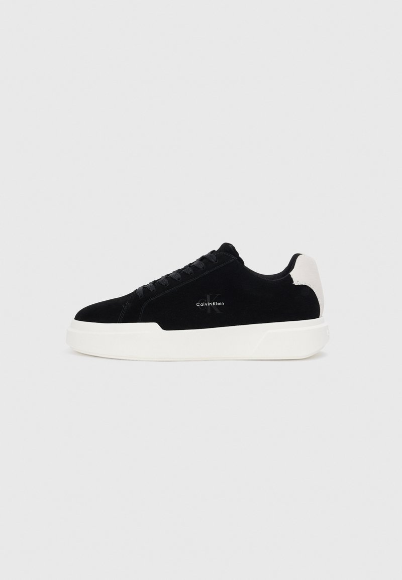 Adidași negri cu talpă albă și tab cu toc alb, cu șireturi în față și logo-ul Calvin Klein pe lateral.